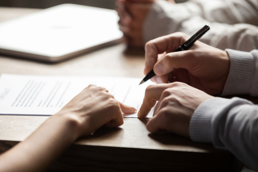 Three people work to sign documentation and paperwork.