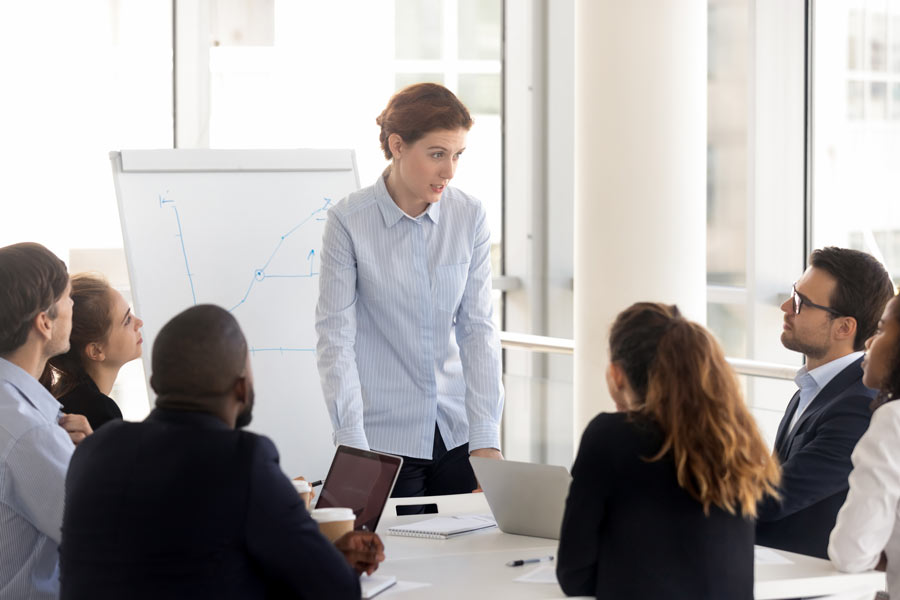 Woman presents an idea to a table of her coworkers in a meeting.