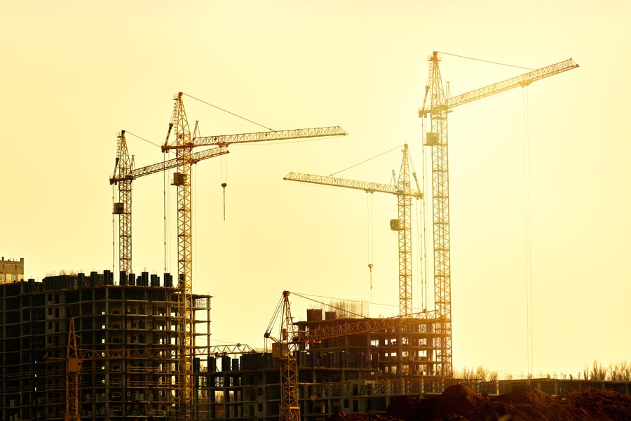 Four cranes work to assemble energy efficient buildings.