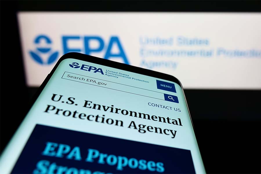 Mobile phone with website of US Environmental Protection Agency (EPA) on screen in front of logo. Focus on top-left of phone display.