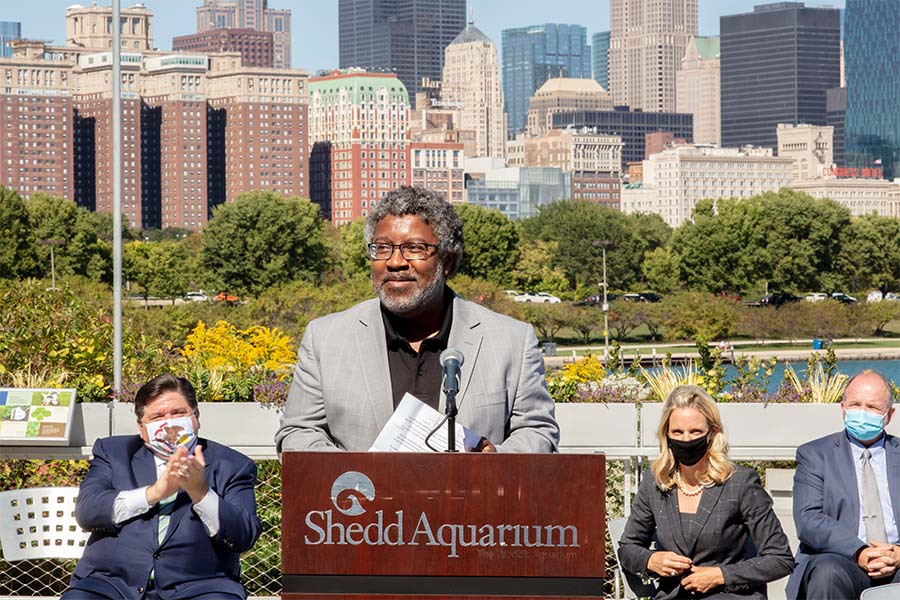 Delmar Gillus, COO of Elevate, stands at a podium infront of Chicago skyline.