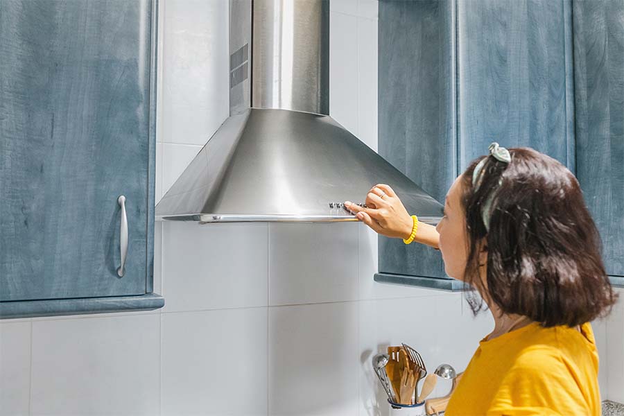 Woman pressing a button on a steel Recirculating Range Hood.