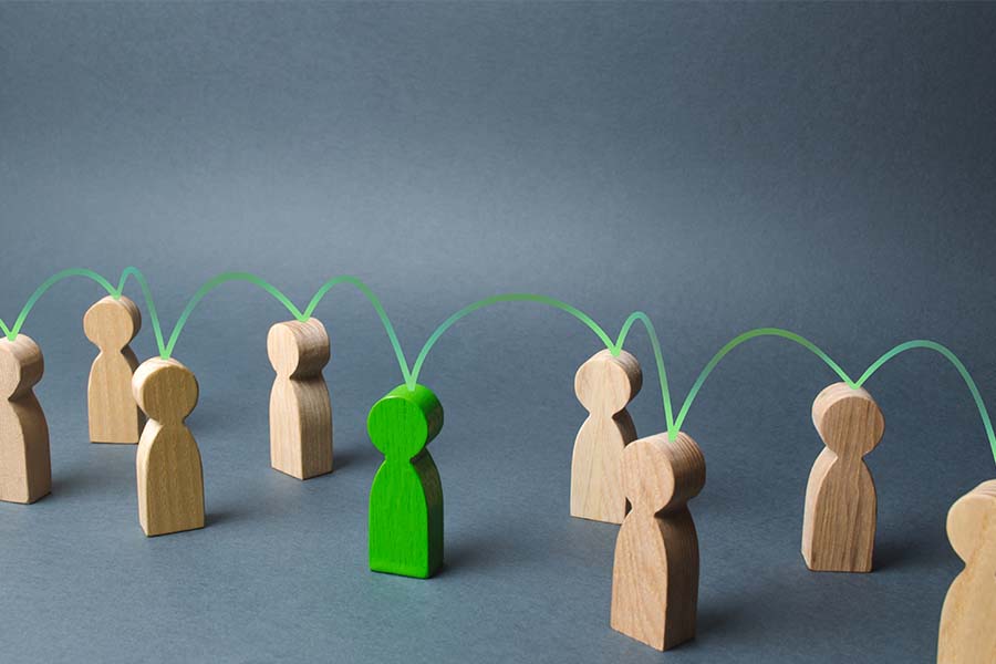Photo of woomen figures that resemble people. The one in the middle is green. They all have green lines connecting them together.
