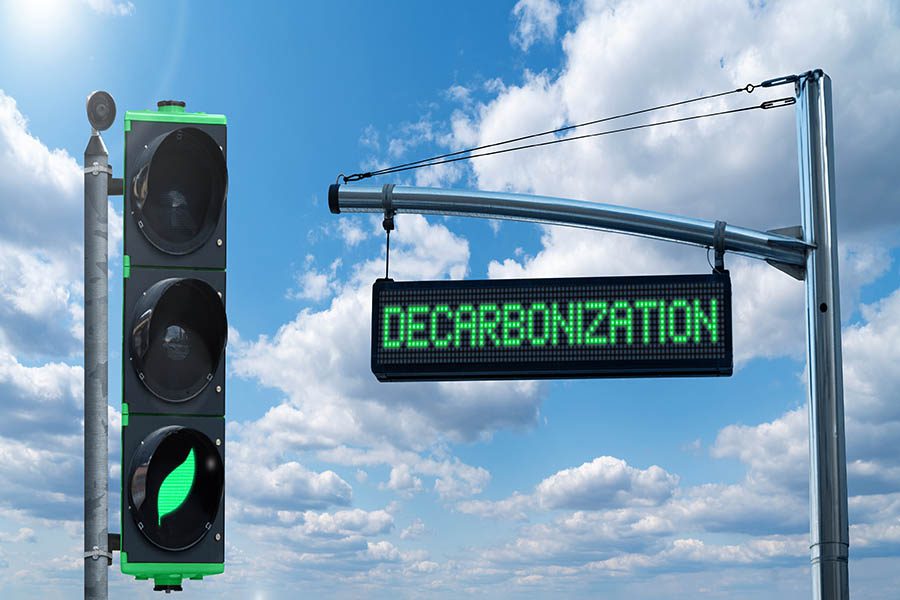 Streetsign that reads "decarbonization" and a green light to the left.