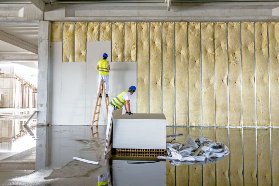 Two workers installing insulation in building
