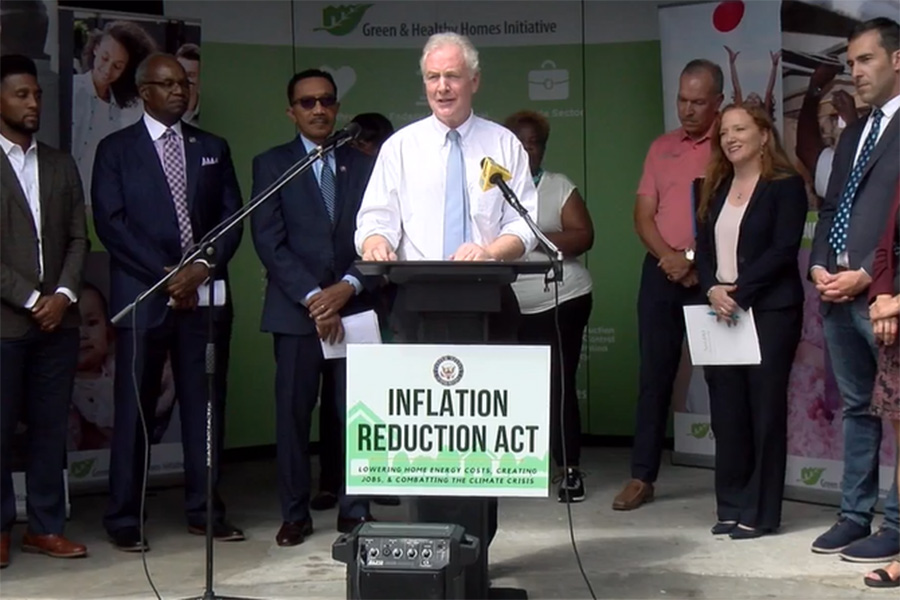 Senator Van Hollen standing at a podium for a press conference with a sign that reads, "Inflation Reduction Act"