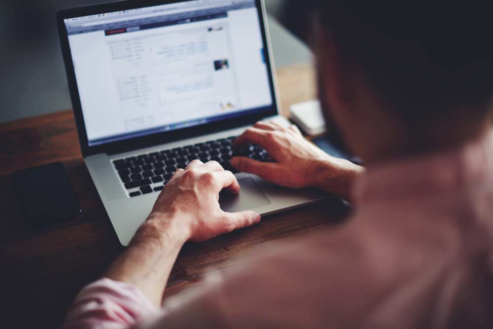 Man searches the internet on a laptop at his desk