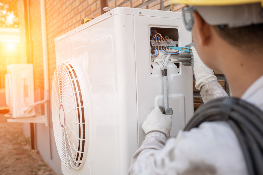 Man tests power and wiring in a heat pump.