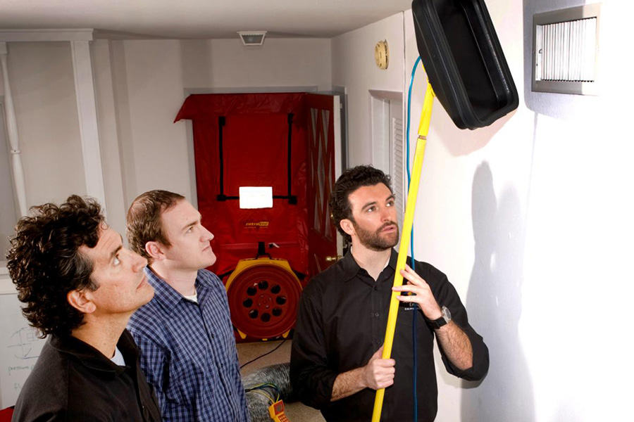 A photo of three men performing a blower door test.