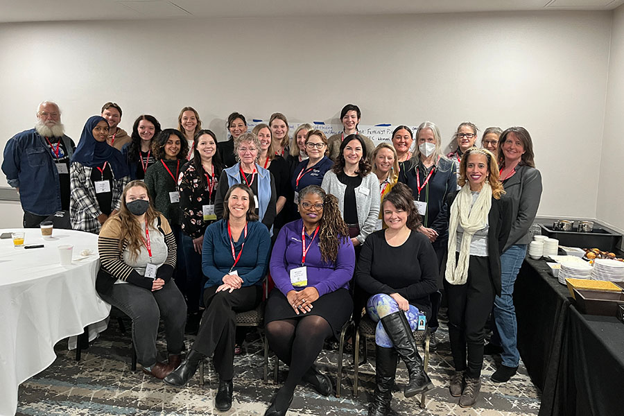 A group working toward progress for women in home performance gathers for a picture.