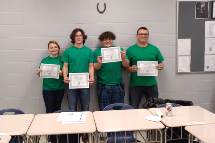 A photo of four people holding up certificates.