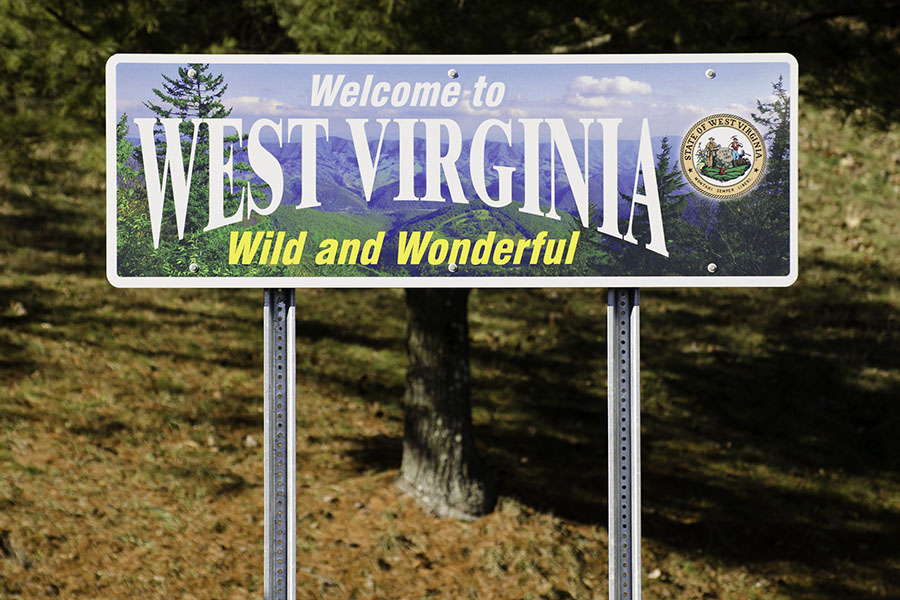A sign that says "Welcome to West Virginia. Wild and Wonderful." It is surrounded by trees and fallen leaves.