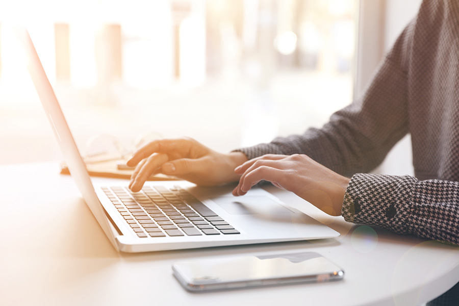 A photo of a person typing on a laptop.