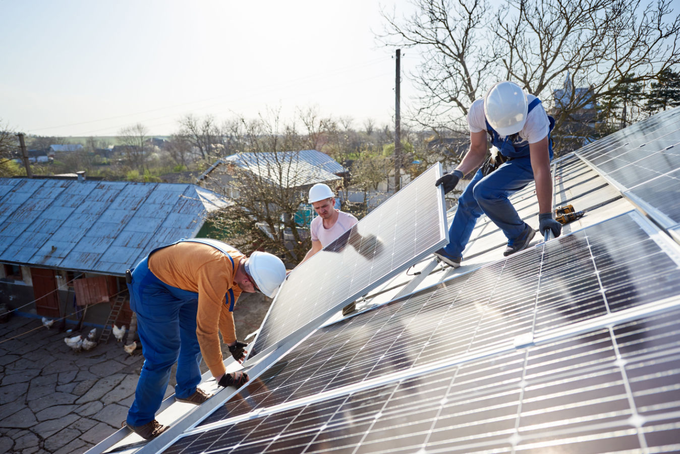 Three person team on a roof installing solar panels.
