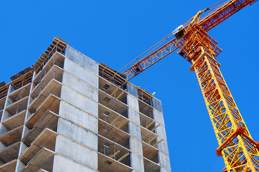 Yellow crane next to a tall building under construction