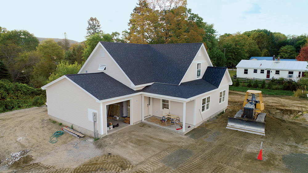 Exterior of a new construction home with the garage door open. There is a tractor in the yard.