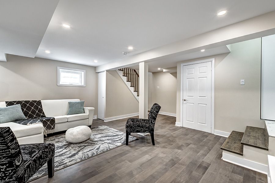 Finished basement living area with a couch, chairs and rug