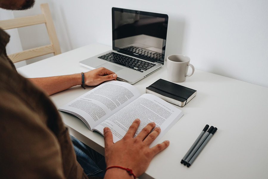 Hands opening a book at a desk