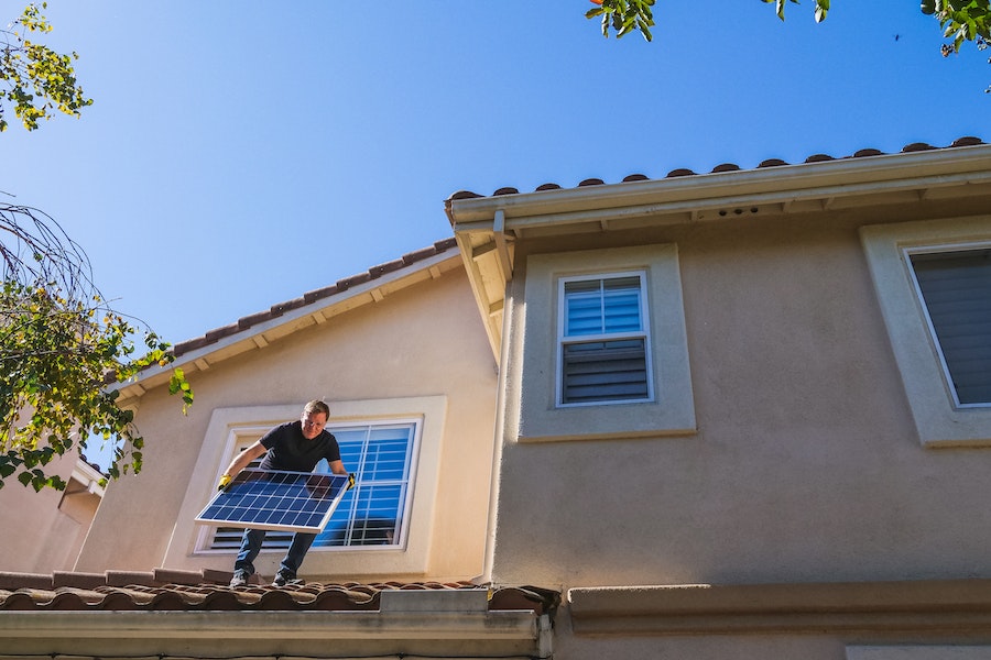 Man installing solar panel on roof of home