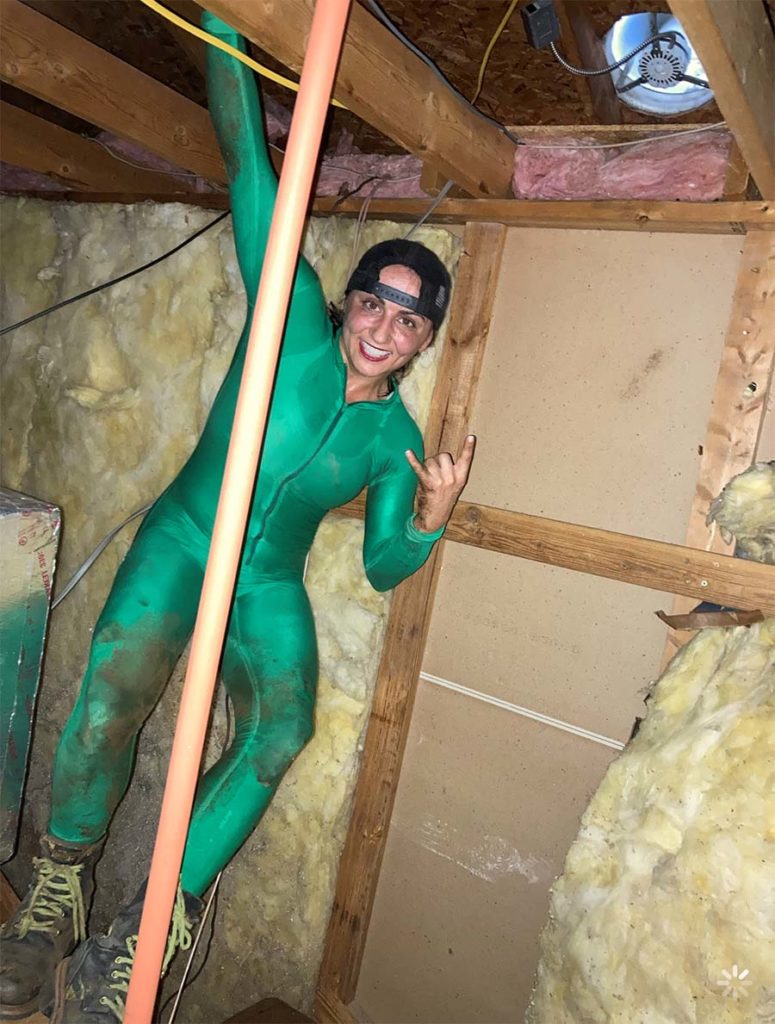 Jessica Azarelo in a body suit inside of the attic of a home. 