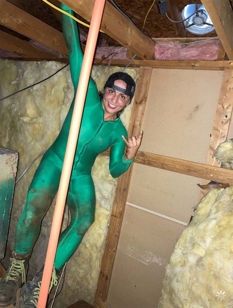 Jessica Azarelo in a body suit inside of the attic of a home.