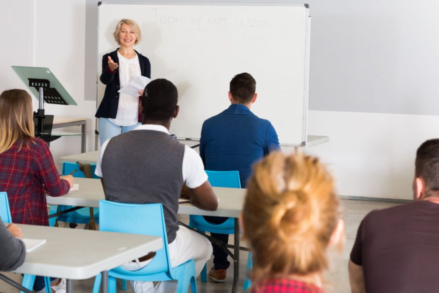 Concentrated adult students of different nationalities with teacher studying in classroom