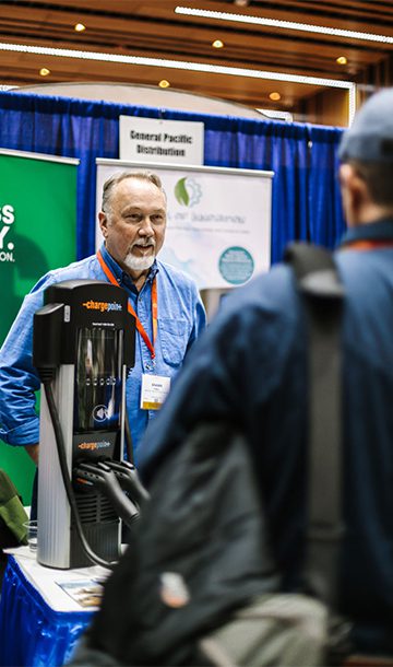 Man at exhibitor booth is talking to another attendee