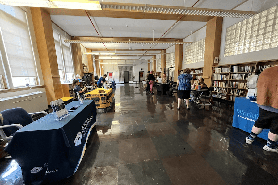 Image of tables at a job fair in the public building displaying various company booths and information