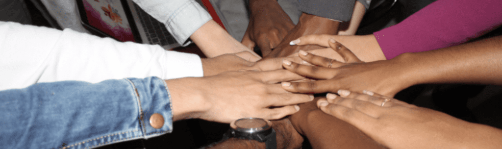 A group of individual hands of all flesh colors meeting in a collective group photo.