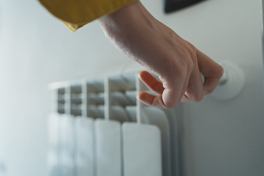 Close up of a hand adjusting the temperature knob on a radiator