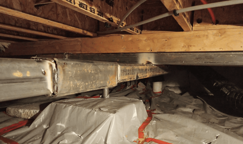 Workers install steel beams under the compromised wood beams to stiffen the foundation and level the house. 