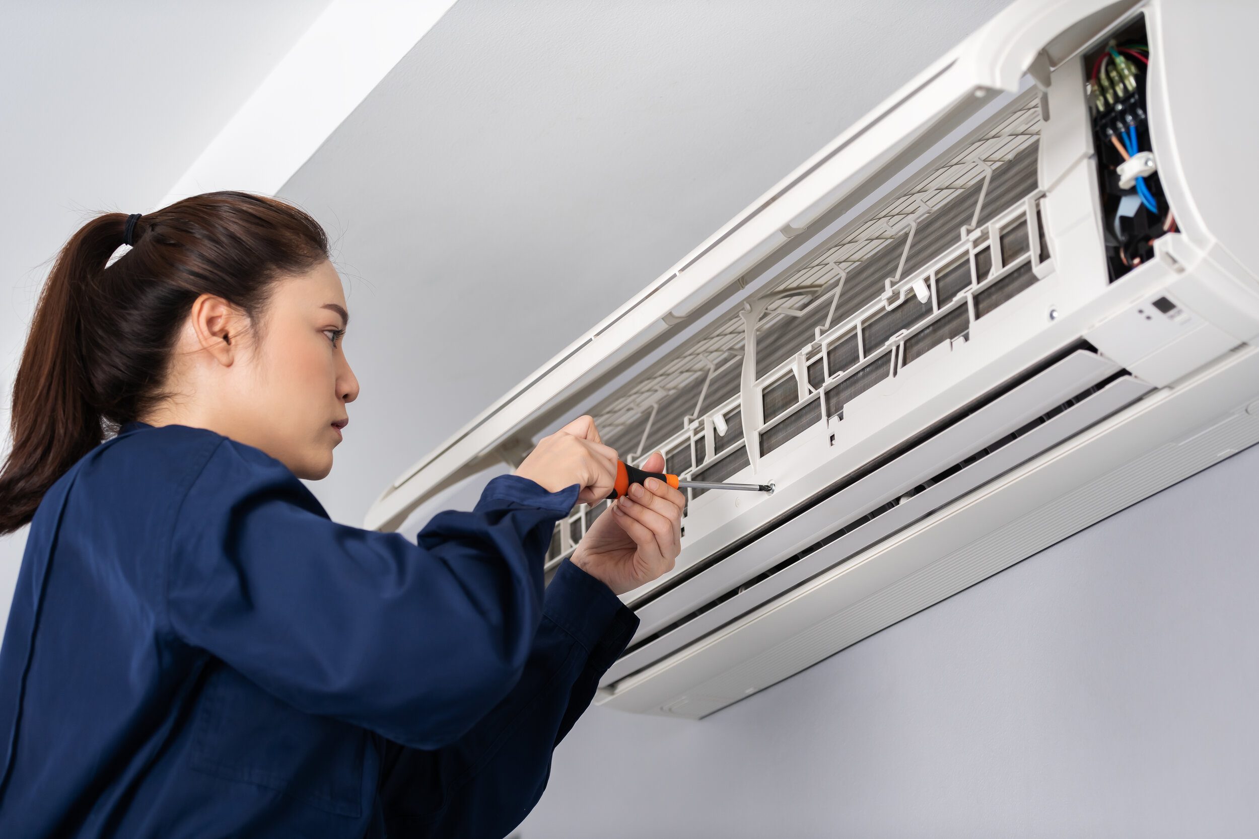 female technician working on mini split heat pump