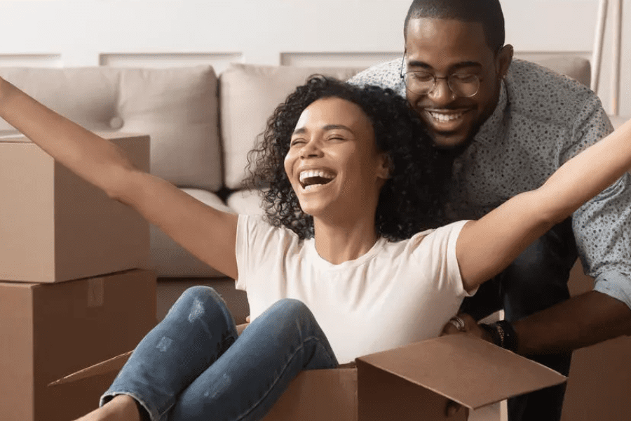 Two people smiling surrounded by moving boxes