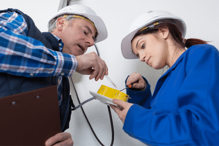 A mentor assisting an apprentice on a job.