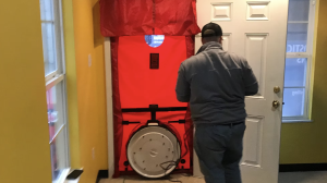 Weatherization pro working doing a blower door test