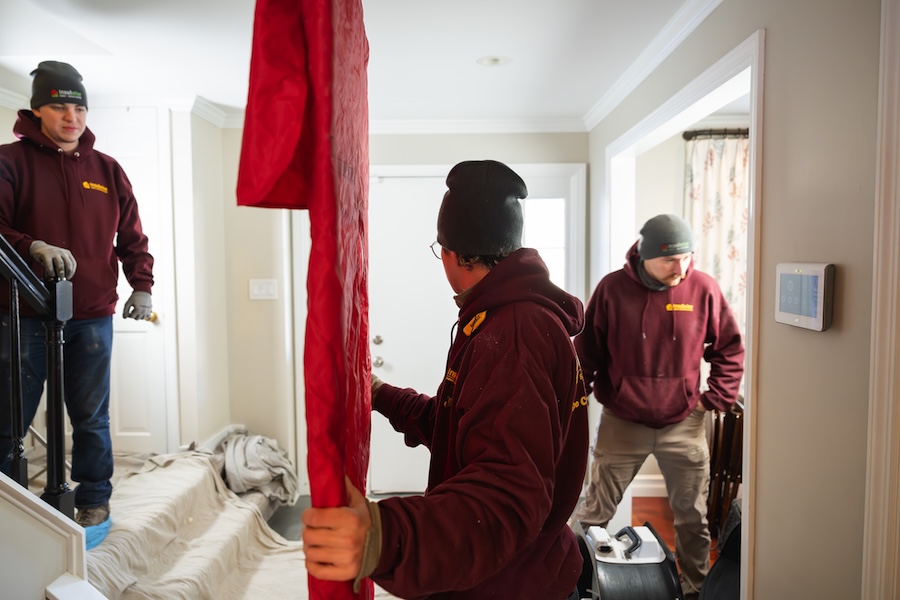 Three home performance workers in a foyer setting up for a job