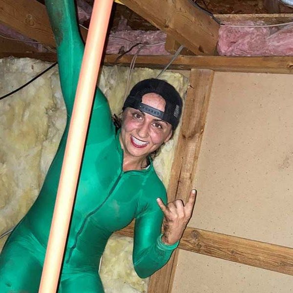 Jessica Azarelo in a body suit inside of the attic of a home.